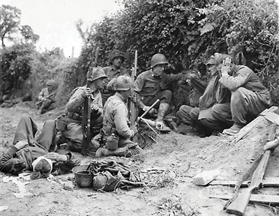 These 4th ID soldiers, moving along a road between dense hedgerows, are in the Normandy breakout. They were excellent concealment for German infantry who burrowed into them from the back side.