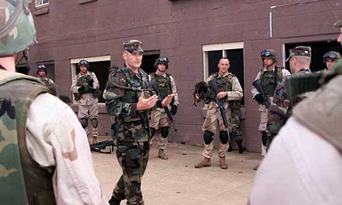 Actors receive instructions on urban patrolling techniques.