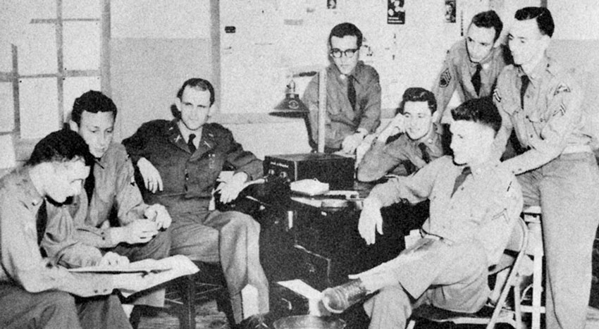 The Publication Platoon’s Propaganda Section: PFC James K. Rowland, SGT David E. Lilienthal, Jr., 1LT John E. Eckenrode, Jr., PFC Virgil M. Burnett, CPL James J. Klobuchar, SGT Robert W. Ferguson, PFC Donald M. Andrews (seated), and CPL Earl W.  ‘Bud’ Moline.