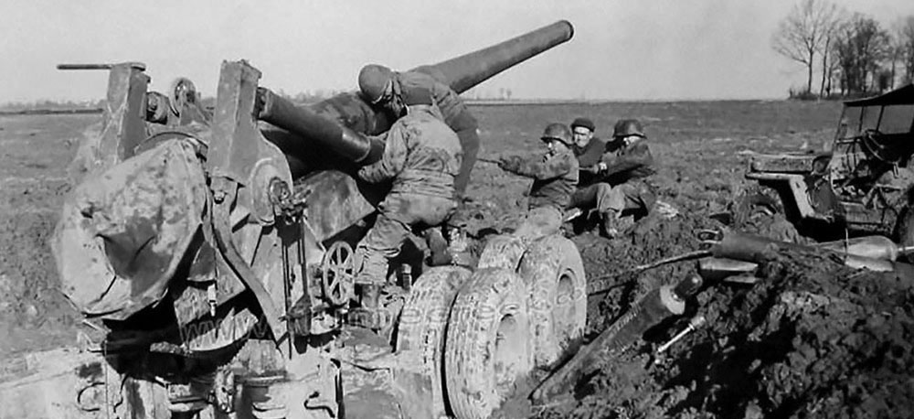 Six cannoneers ‘manhandling’ a 155mm ‘Long Tom’ stuck in French mud