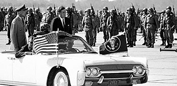 President Kennedy &lsquo;trooped the line&rsquo; of paratroopers with Lieutenant General (LTG) Thomas J.H. Trapnell, the Third U.S. Army commander, from his &lsquo;signature&rsquo; Lincoln <i>Continental</i> convertible.