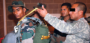 ODA 1413 Team Sergeant MSG Stanley Rivacoba, Jr.* demonstrates a Jumpmaster Personnel Inspection (JMPI) on a PARA (SF) soldier at JBLM on 15 August 2011.  1st SFG and PARA (SF) personnel conducted the combined jump using MC-6 parachutes the following day.