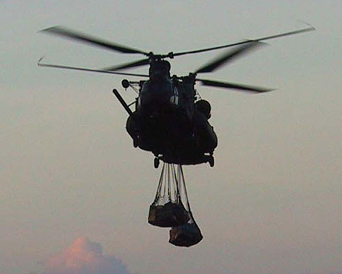 MH-47E moves out at dusk with a sling-load of supplies