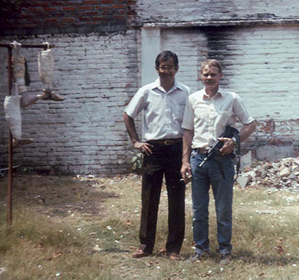 Jim Cloud and chief Salvadoran prosthesis technician in the patio of the shop with the &ldquo;tree of death&rdquo; behind them to the left.