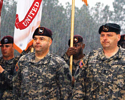 Colonel Hector Pagan, USASOC Deputy Commander, Colonel Ferdinand Irizarry, 95th Civil Affairs Brigade Commander, and Command Sergeant Major Timothy Strong, 95th Civil Affairs Brigade Command Sergeant Major, prepare to unveil the new 95th Civil Affairs Brigade Colors at Fort Bragg on 16 March 2007 during a rainstorm.