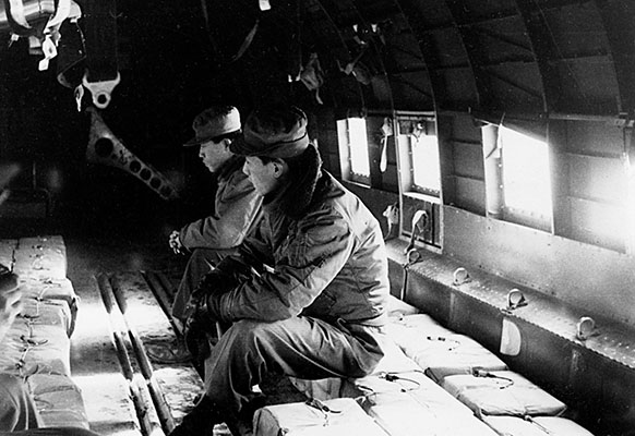 Korean soldiers assigned as “door kickers” wait for the time to drop. Visible on the leaflet “bricks” or bundles are fuse igniters. Before throwing the brick, the fuse igniter was pulled. Once clear of the aircraft the time fuse would ignite the blasting cap and the leaflets would scatter.