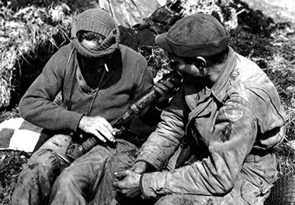 Two Forcemen examine a Japanese Type 89 50mm grenade launcher, known to the GI&rsquo;s as a &ldquo;knee mortar,&rdquo; found during a patrol on Kiska. The man on the right is wearing both the First Special Service Force patch and that of ATF-9, &ldquo;Corlett&rsquo;s Long Knives.&rdquo;