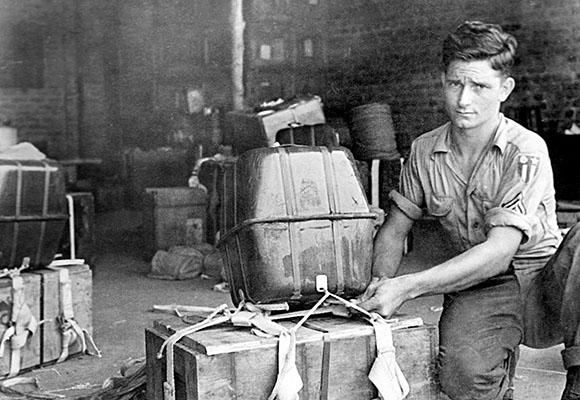 An OSS enlisted man attaches a parachute container to an ammunition crate. Critical items like ammunition and radios were air-dropped by parachute.