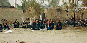 While the first enemy fighter to surrender was being searched, a group of forty women and children materialized from the compound and sat down.