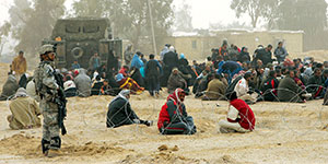 2/3 Infantry Stryker soldier guards the detainees being held in makeshift concertina enclosures.