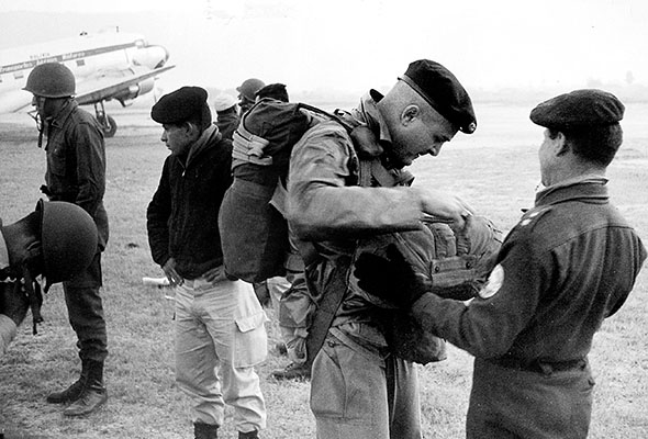 MAJ John D. Waghelstein, the SF advisor to the Airborne Battalion and Parachute School and COIN instructor at la Escuela de Armas (Combat Arms School) prepares to jump with a group of Bolivian airborne trainees at Cochabamba.