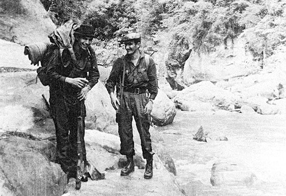 “Miguel,” Cuban Manuel Hernández Osorio, a Sierra Maestra veteran, and “Inti,” Bolivian Guido Peredo Leigue (right), pause after a river crossing during the “Long March.” Notice the rocky river valley (or canyon) terrain the guerrillas moved over.
