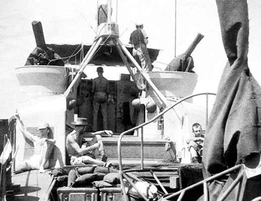 When allowed on deck of P-564, non-crew members were to stay in the small area behind the bridge. On the bridge, one man is at the wheel while another keeps watch.