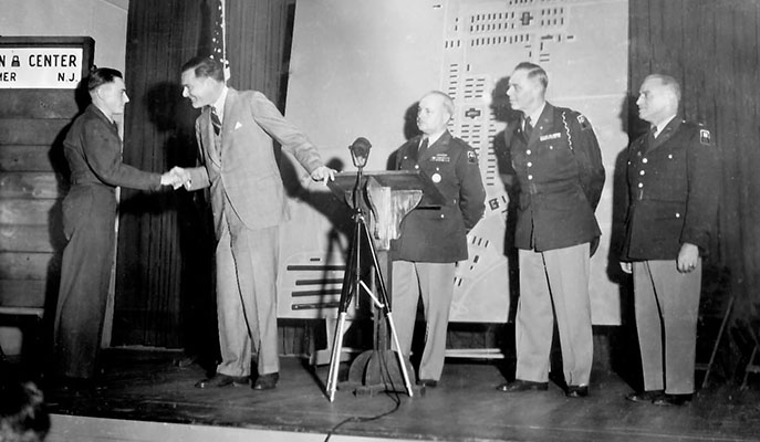 Senator Henry Cabot Lodge, Jr. shakes hands with Private Stanislaw P. Nowalski (Poland) in Havens Hall, Camp Kilmer, NJ on Sunday, 14 October 1951.