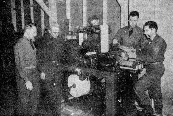 LTC Frank McCulloch presses the &ldquo;Start&rdquo; button as CPT Otto Bennett looks on. PVT Rus, 1LT Peter A. DeFranco, and SGT Gilbert examine the first copies of an offset press-printed <i>Psyn-post</i> in Building 193, Fort Riley.