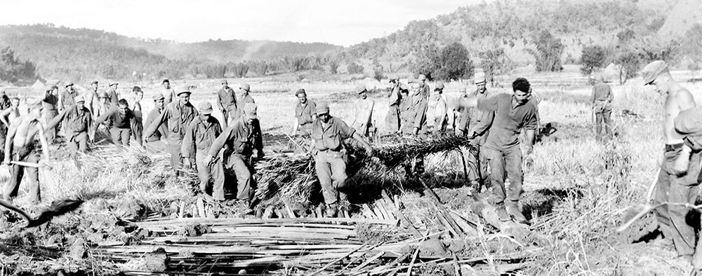 MARSmen had to reduce obstacles on potential landing strips while on the march so that wounded or sick soldiers could be evacuated. Here, local roofing material followed by earth, was used to cover a trench.