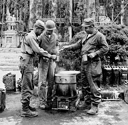 Members of TF INDIANHEAD set up their kitchen in front of the North Korean capitol building in P&rsquo;yongyang, shown here in defensive camouflage. This building became Eighth Army Headquarters.