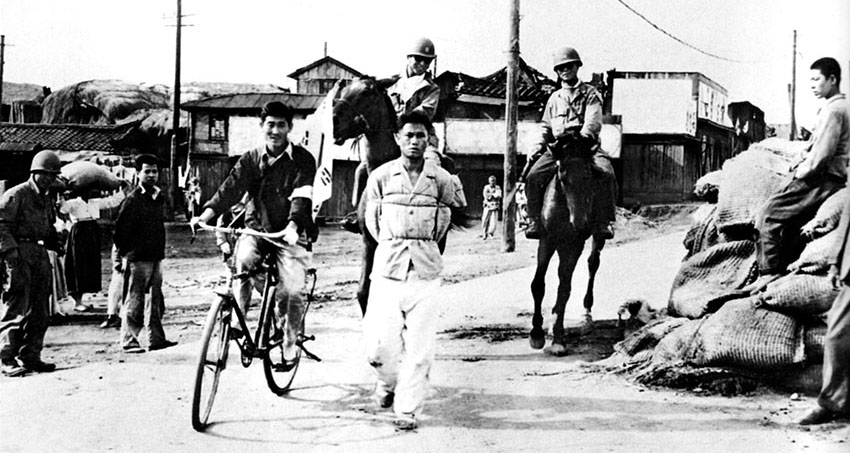 Mounted South Korean soldiers &ldquo;ride herd&rdquo; on a prisoner as he is marched through a P&rsquo;yongyang street to a prisoner-collection point.
