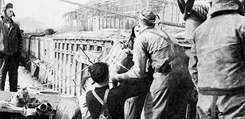 U.S. Navy demolition teams rig explosives to a pier at Hungnam.