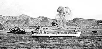 The USS Begor (APD-127) on left and last LST off Hungnam as the demolition begins.