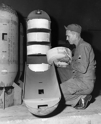 SFC Furl A. Krebs, 3rd Reproduction Company, loads an M11191 cluster bomb adapter with 22,500 (5&rdquo; X 8&rdquo;) rolled Psywar leaflets at the FECOM Print Plant. 