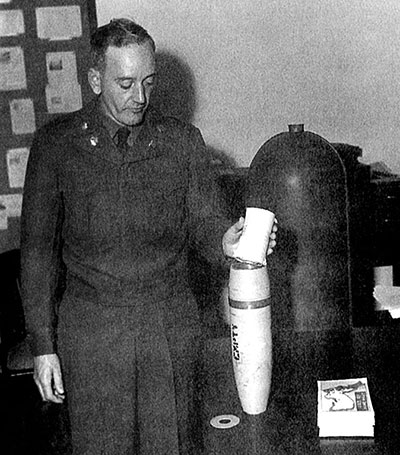 SSG Mason, X Corps Psywar, shows how a roll of 400 Psywar leaflets fits in a 105 mm howitzer smoke canister shell.