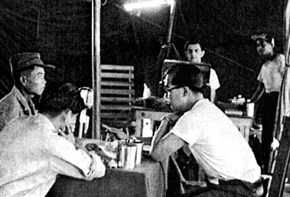 1LT Calvin J. Sing (glasses) interviews a Chinese POW while SGT Sol S. Gamis records the session for future broadcast.