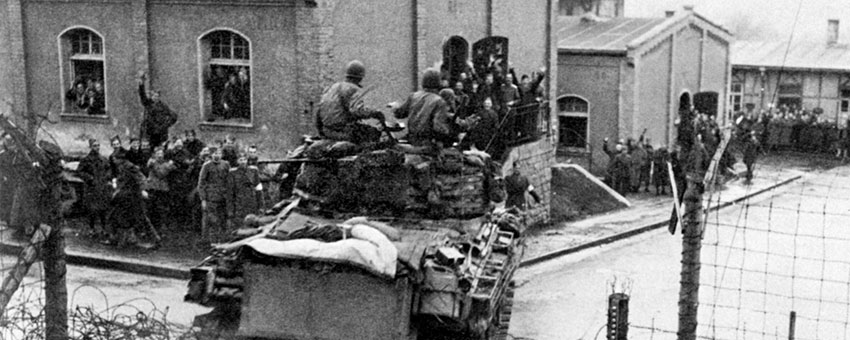 A Sherman tank of the 14th AD smashes into a German camp holding Allied POWs.