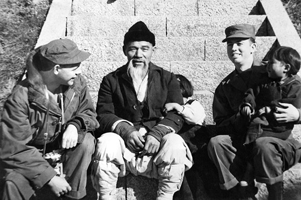 CPLs Bill Morton and Joe Dabney get their picture taken alongside a Korean papa-san and his children in Pusan.