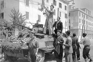 Standing aside the turret of this M-8 armored car, a member of Radcliffe's patrol raises the flags of the United States and Canada so that they may be documented by the accompanying photographers. 