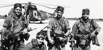 Sergeant First Class (SFC) Adderly carrying an M16A1 rifle, a M79 40mm grenade launcher, and two M72 Light Antitank Weapon (LAW) Rockets.